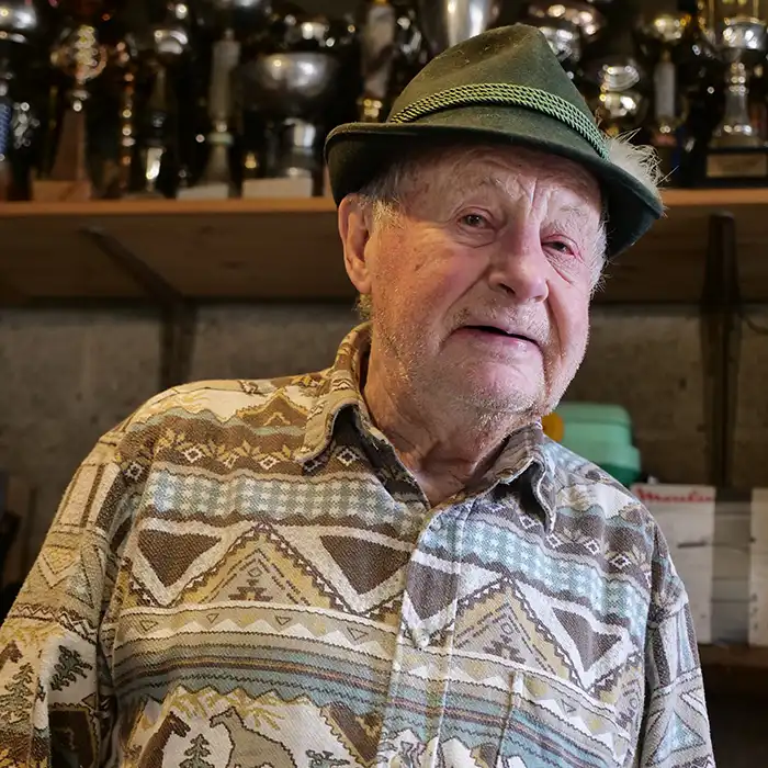 Portrait de Julien au sourire espiègle. Derrière lui, des coupes et des médailles.